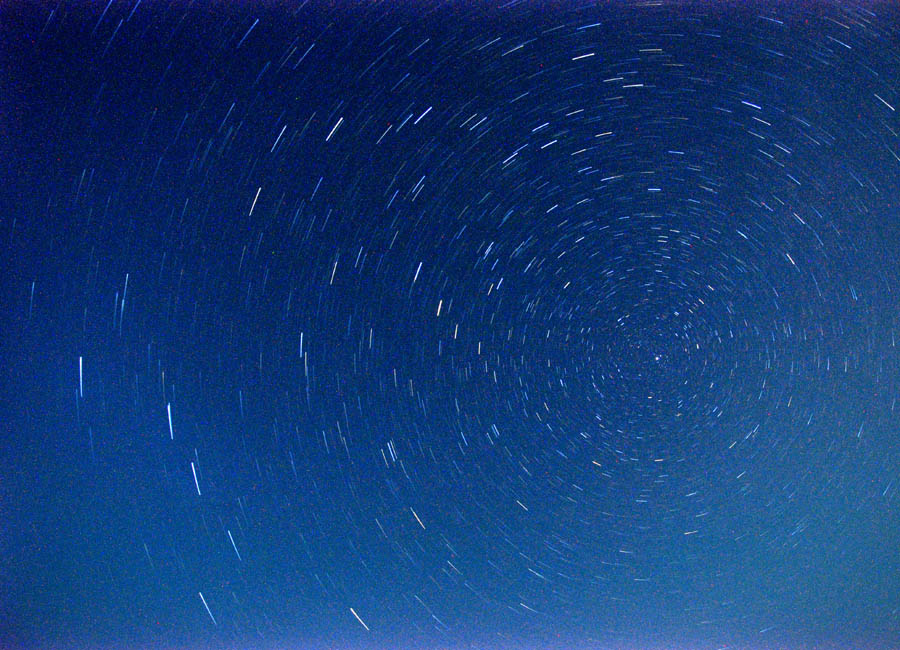 Time exposure of stars above a Lake Michigan beach.