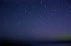 Time exposure of stars above a Lake Michigan beach.